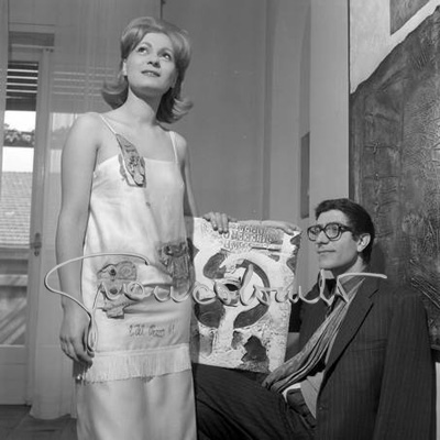 Lucio Del Pezzo con una indossatrice. Sfilata dei modelli disegnati dagli artisti per l'Atelier di Bruna Bini e Giuseppe Telese. Milano, marzo 1961